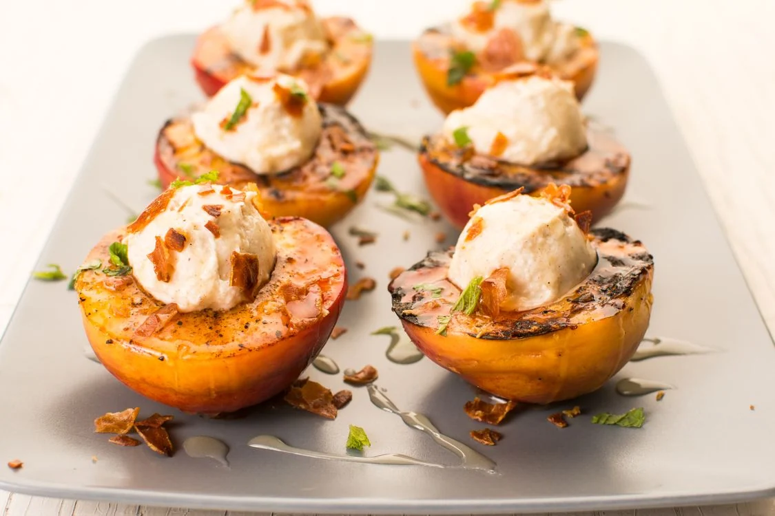 Grilled peach halves topped with a creamy scoop, sliced almonds and fresh mint