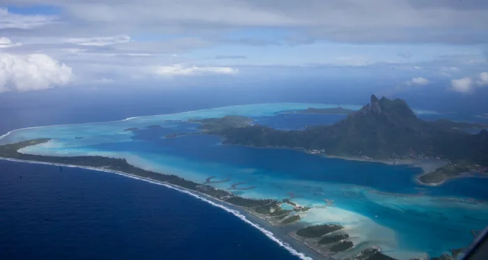 Bora Bora and its volcanic peaks enclosed by a turquoise lagoon