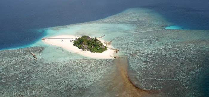 A small Maldivian island surrounded by sand and coral shallows