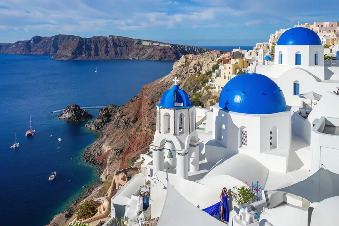 Three blue domes in Oia above Santorini’s caldera