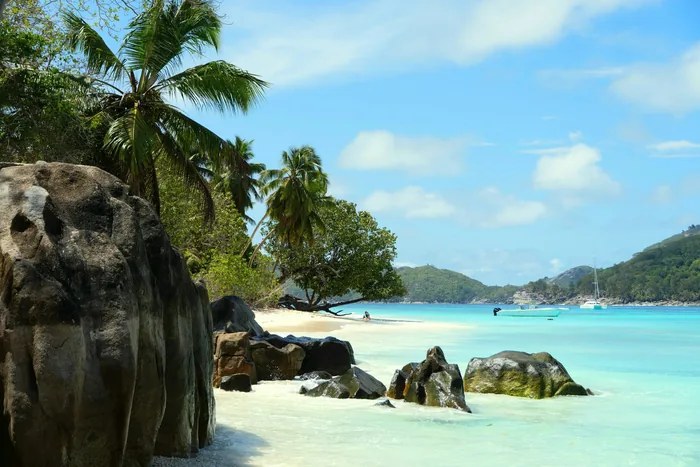 Granite boulders, palms and clear water in the Seychelles